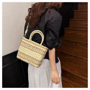 Detail of woven straw tote bag featuring geometric patterns and detachable shoulder strap