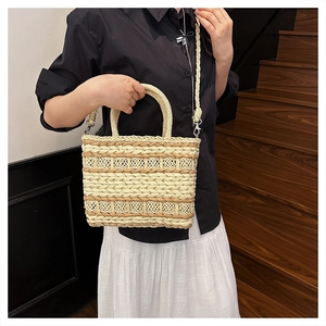 Detail of hand-woven straw bag with striped hollow pattern and circular handle for summer