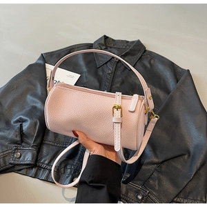Detail of pink cylinder barrel bag with pebbled leather texture and gold hardware
