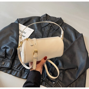Detail of cream-white cylinder bag featuring premium litchi grain texture and gold hardware