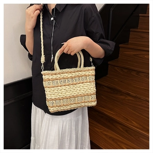 Detail of hand-woven straw crossbody bag styled with a summer outfit on wooden stairs
