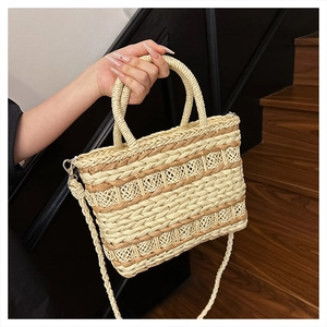 Detailed close-up of a woven straw handbag with dual handles and a detachable strap