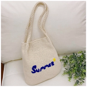 Detail of Summer embroidery and floral accent on cream crochet straw tote bag