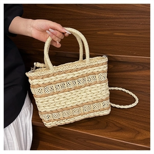 Detail of hand-held straw woven bag with contrast stitching and metallic buckle