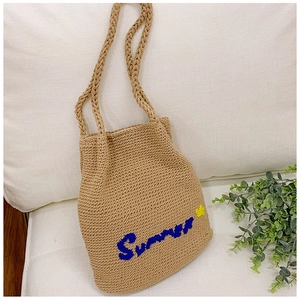 Detailed close-up of straw tote bag with Summer embroidery and floral knitting patterns