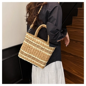 Detail of striped straw tote bag featuring round handles and woven strap for shoulder carry
