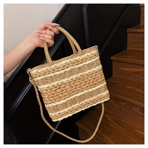 Detail of handwoven straw bag featuring beige and ivory stripes with a top handle