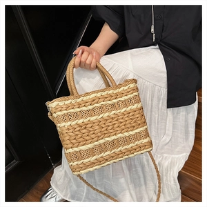 Detail of hand-woven straw crossbody bag with beige and tan stripes and round handle