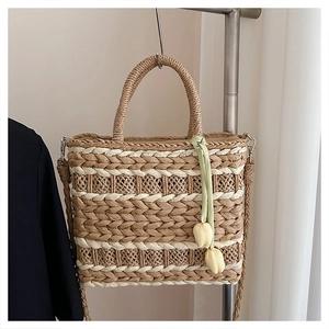 Detail of hand-woven straw tote with tulip charm decoration for summer beach travel