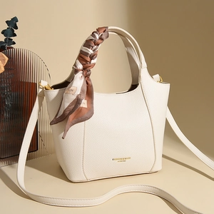 Close-up of cream leather tote bag with silk scarf handle and golden hardware detail