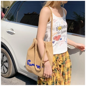 Detail of hand-woven beige straw tote bag with blue Summer embroidery for beach holidays