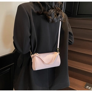 Detail of light pink pebble leather barrel bag with gold hardware and fine shoulder strap