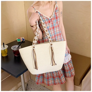 Detailed close-up of straw tote bag featuring wood ring handles and stylish tassels