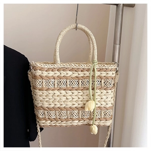 Detail of woven straw tote bag texture with yellow tulip pendant and circular handle