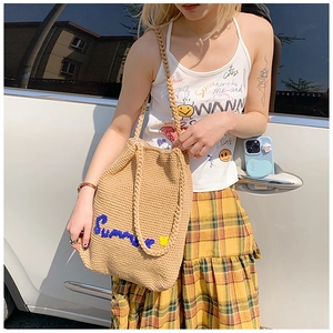 Detail of Summer embroidery and yellow floral accents on woven straw bucket bag