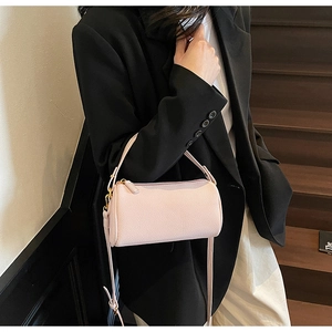 Detail of light pink barrel bag with lychee texture leather and gold metal hardware