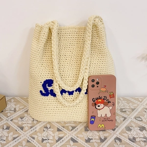 Detail of handmade crochet texture on large cream straw bag with blue Simple lettering