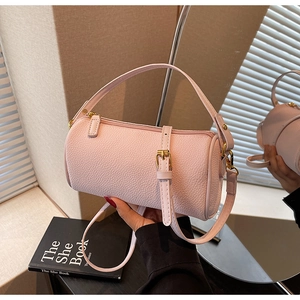 Detail view of pink pebbled leather cylinder bag with gold hardware and top handle
