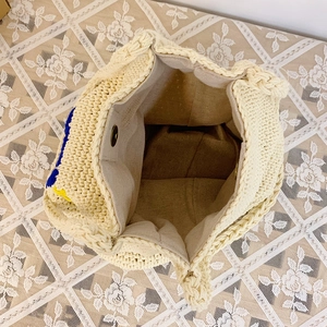 Detail showing inner canvas lining, spacious capacity and bronze magnetic clasp of the woven bag