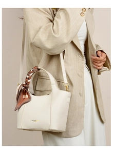 Detail of cream white leather tote with silk scarf handle and gold embossed logo text