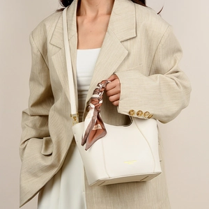 Detail of off-white leather tote bag with silk scarf handle and gold lettering