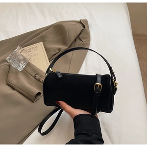 Top view of black leather cylinder bag with gold hardware and stylish office accessories