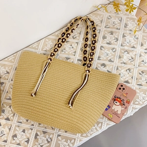 Detail of bohemian straw tote bag with braided handles and decorative rope tassels