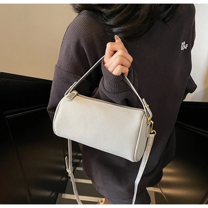 Detail of white lychee texture cylinder bag with golden hardware and adjustable strap