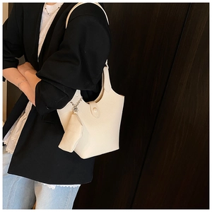 Close-up of beige leather bucket bag with mini coin purse on dark wood background