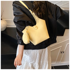 Detail of light yellow crescent bucket bag featuring textured leather and mini pouch