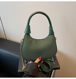 Detail of dark green woven hobo bag featuring a chic gold chain and curved handle