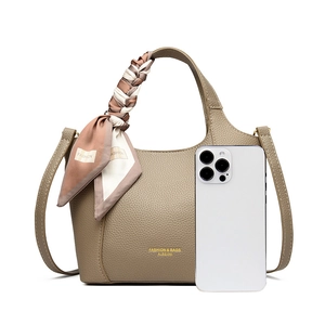 Detail of khaki pebbled leather tote with decorative silk scarf and smartphone for scale