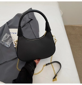 Detail of black crescent hobo bag featuring wave pattern texture and gold chain strap