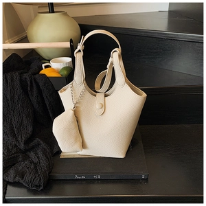 Close-up of beige bucket bag with lychee texture and hanging mini coin purse detail