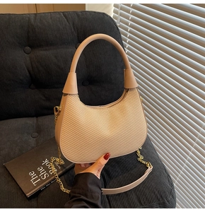 Detail of hobo bag with woven texture, beige leather trim and golden chain strap