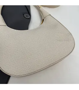 Close-up of beige moon bag showing woven fabric texture and gold metal accents