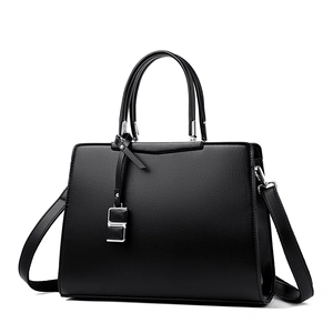 Sac à main élégant en cuir noir grainé avec pendentif argenté et bandoulière amovible