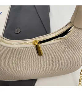 Close-up of beige woven texture handbag with golden metal zipper and chain details