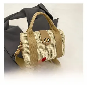 Detail of woven straw bucket bag with khaki straps and golden metallic twist lock