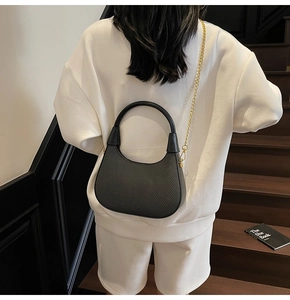 Back view of black woven hobo bag with gold chain strap on model for stylish look