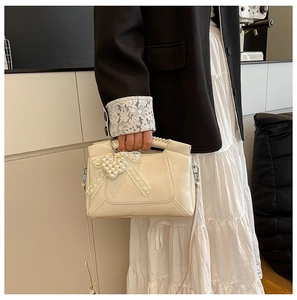 Detail of cream white leather bag with lace bow and pearl heart pendant decoration