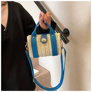 Detail of woven straw bag featuring blue fabric handles and gold twist lock closure