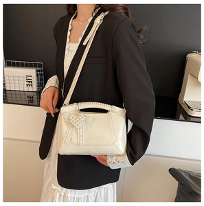 Chic cream shoulder bag with pearl heart charm and lace bow shown in a street style setting