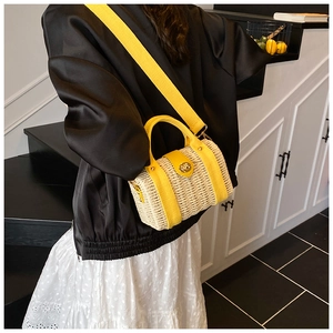 Detail of hand-woven straw bucket bag with yellow canvas straps and golden buckle