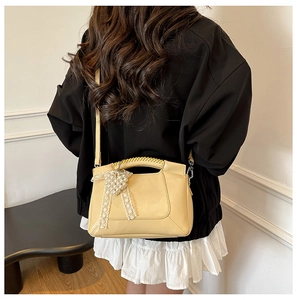 Close-up of creamy yellow handbag with pearl heart charm and lace bow details