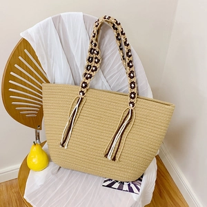 Handwoven straw shoulder bag with beaded handles and long tassels for a boho summer look