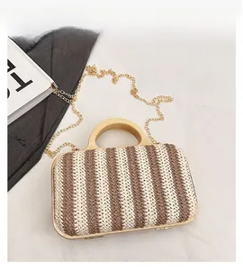 Close-up of a striped woven straw tote with wooden handles and a gold metal chain strap