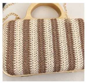 Close-up of hand-woven striped straw handbag with wooden handle and metal chain detail
