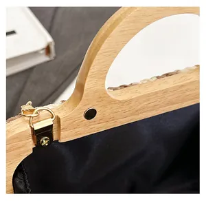 Detail of wooden handle with magnetic clasp and black fabric lining on woven straw bag