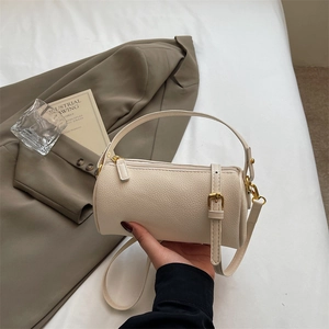 Chic off-white cylinder handbag in lychee leather with adjustable shoulder strap